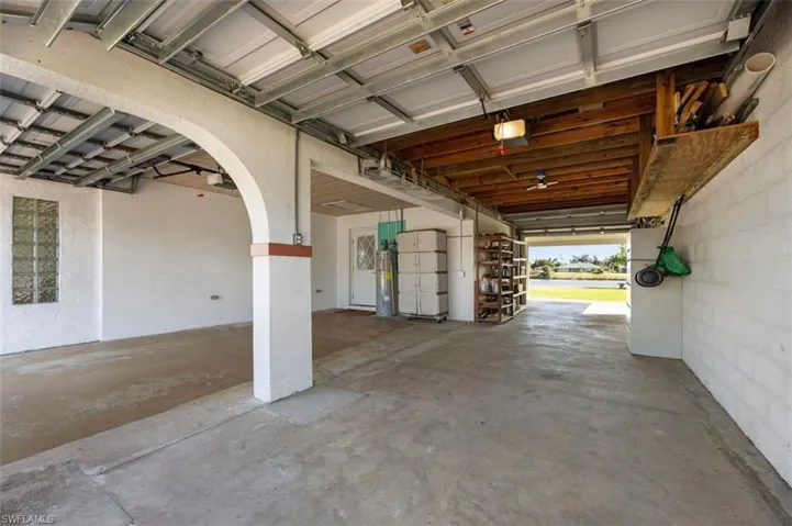 Garage with electric water heater, concrete block wall, and a garage door opener
