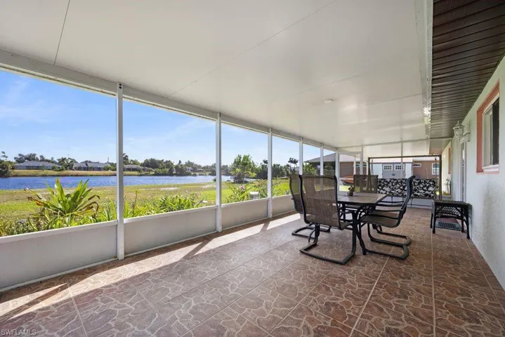 Sunroom / solarium with stone floors, a water view, and outdoor dining space