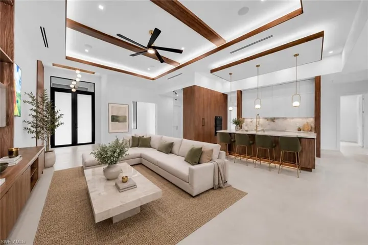 Open-concept living area with a coffered ceiling featuring wood-finish beams and recessed lighting