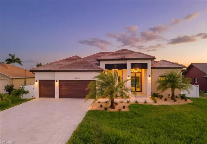 Contemporary stucco exterior with a tile roof, paver driveway, and wood-finish garage doors