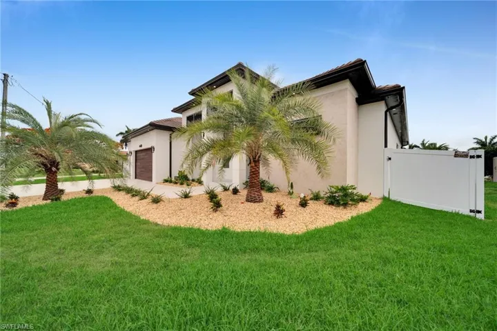 Contemporary stucco exterior featuring a two-story design, a dark wood-finish garage door, and a white privacy fence