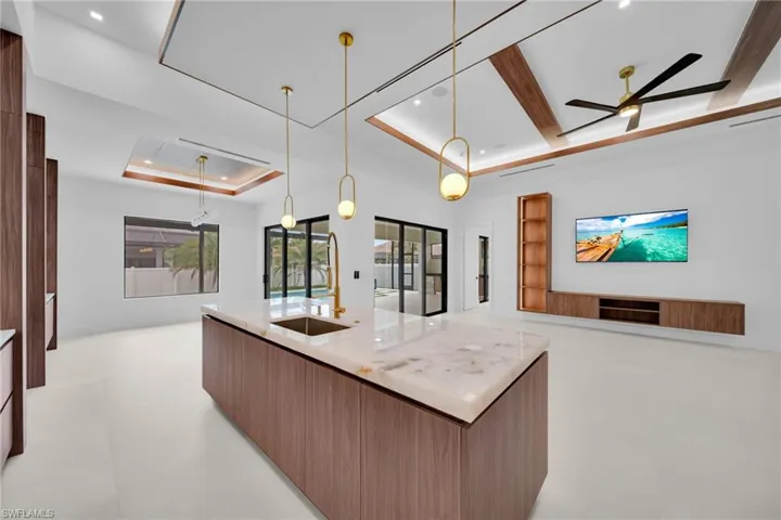 Expansive kitchen island with a stone countertop and integrated sink featuring a gold-tone faucet