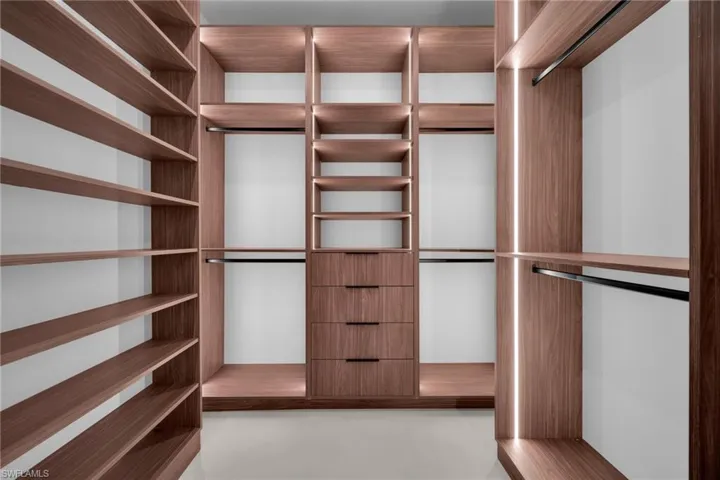 Custom walk-in closet featuring wood-finish cabinetry and integrated lighting