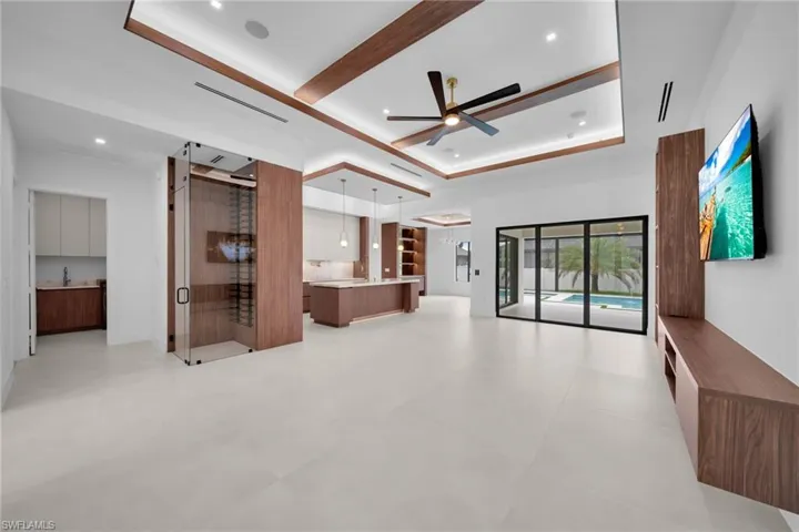 Open-concept interior featuring large format tile flooring, a glass-enclosed wine cellar, a contemporary ceiling fan, and a built-in media console