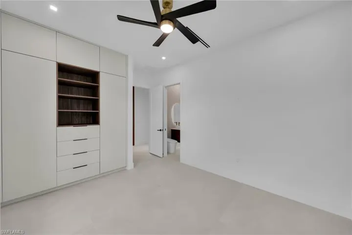 Built-in cabinetry with open shelving and drawers, a modern ceiling fan with integrated lighting, recessed ceiling lighting, light-toned tile flooring, and a neutral wall finish