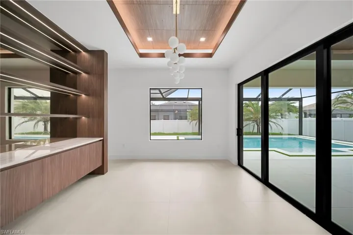 Contemporary interior featuring a wood-finish ceiling accent with recessed lighting and a decorative chandelier