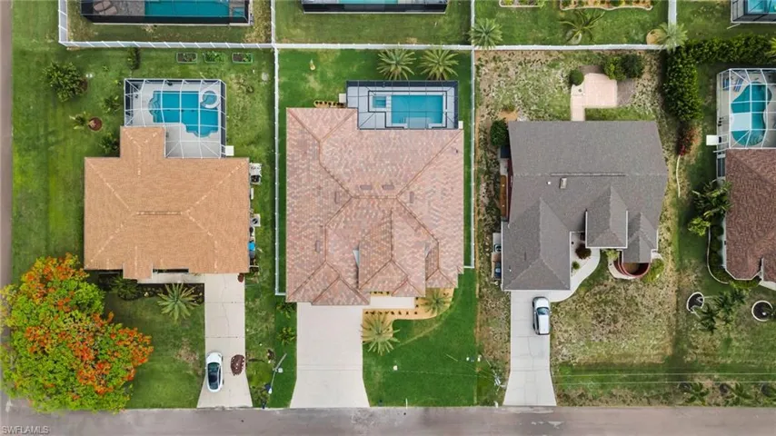 Residential property featuring a screened-in swimming pool with an integrated spa, a paved driveway, and a shingle roof
