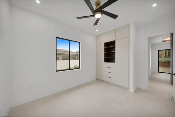 Bedroom featuring a built-in wardrobe with open shelving and drawers, a black-framed window, a contemporary ceiling fan with integrated lighting, recessed ceiling lights, and light-colored flooring