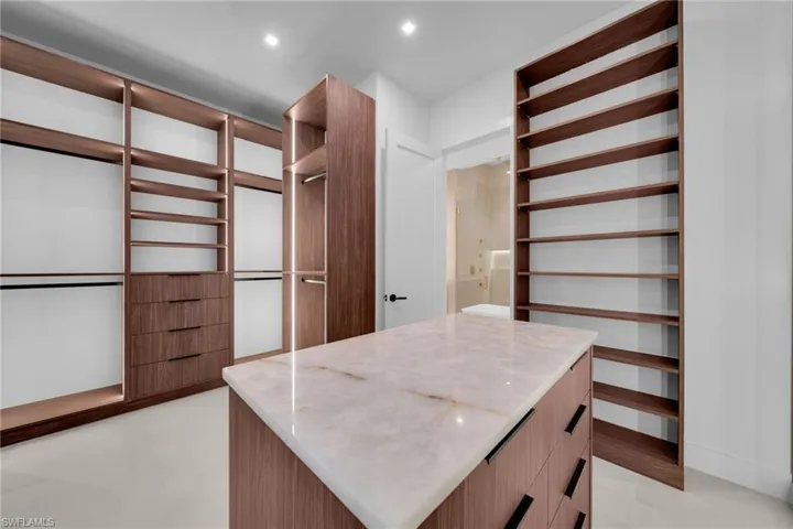 Custom closet system with wood-finish cabinetry and integrated lighting