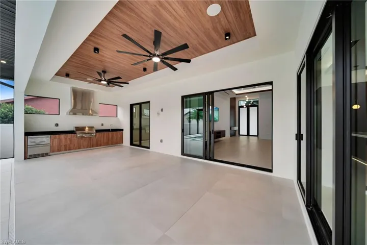 Spacious outdoor living area with a wood-finish ceiling, dual ceiling fans, and recessed lighting