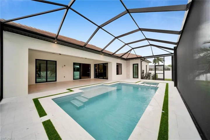 Screened lanai featuring a swimming pool, integrated spa, and expansive patio