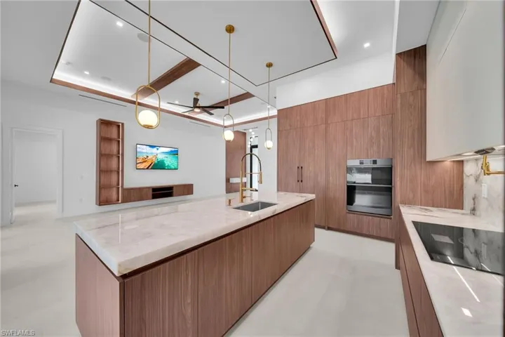 Modern kitchen featuring a large island with a light-toned countertop, integrated sink, and gold-finish faucet