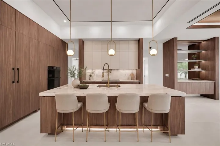 Kitchen island with a light-toned stone countertop, integrated sink, and modern gold-finish faucet