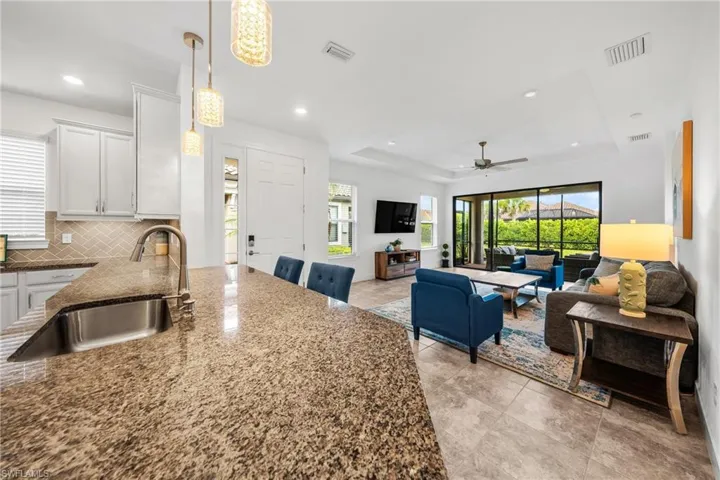 Kitchen featuring white cabinetry, stainless steel appliances, speckled countertops, and a patterned tile backsplash