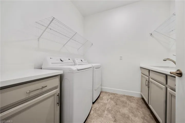 Dedicated laundry area featuring a utility sink, light gray cabinetry with brushed nickel hardware, and light-toned countertop surfaces