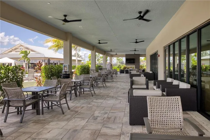 Expansive covered outdoor patio featuring a neutral-toned paver floor, multiple ceiling fans, and recessed lighting