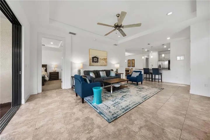 Open-concept living area featuring tray ceilings, recessed lighting, and tile flooring