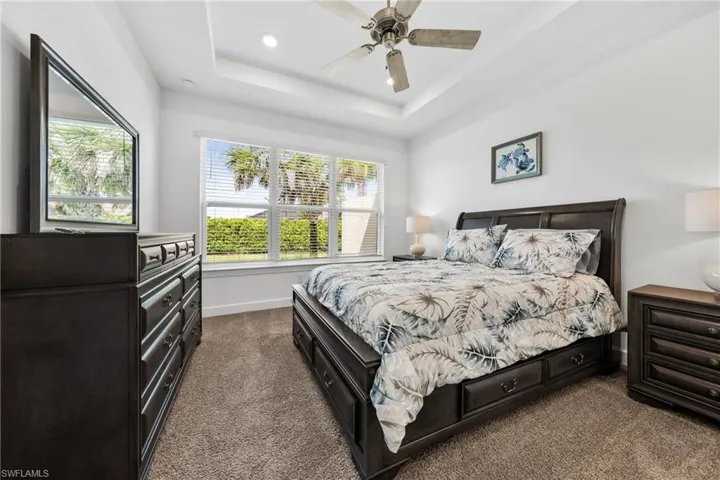 Spacious room featuring a tray ceiling with a ceiling fan, recessed lighting, and expansive windows