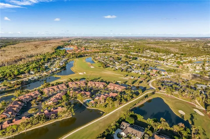 Aerial view of residential area featuring a golf course and a nearby body of water