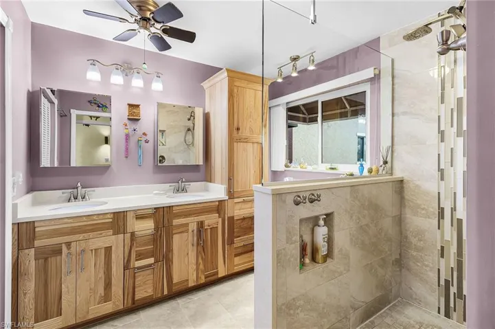 Full bath with double vanity, ceiling fan, and walk in shower