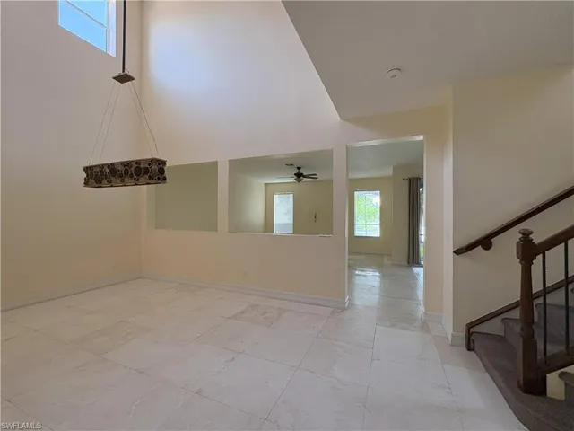 Spare room with stairway, a high ceiling, and ceiling fan