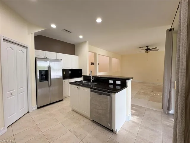 Kitchen with appliances with stainless steel finishes, light tile patterned floors, white cabinetry, ceiling fan, and recessed lighting