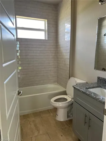 Bathroom featuring vanity, shower / washtub combination, and a textured wall