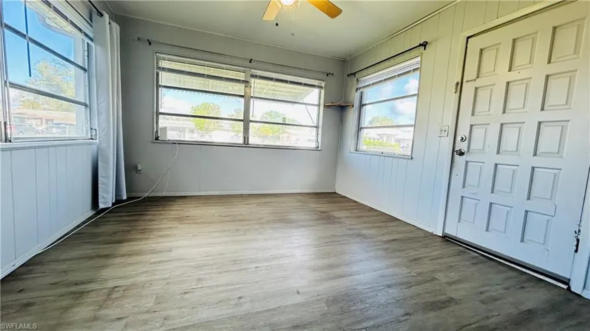 Foyer entrance featuring wood-type flooring, wooden walls, ceiling fan, and a healthy amount of sunlight