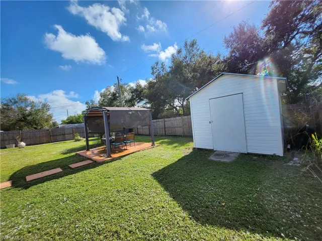 View of huge fenced yard with a storage shed and a patio