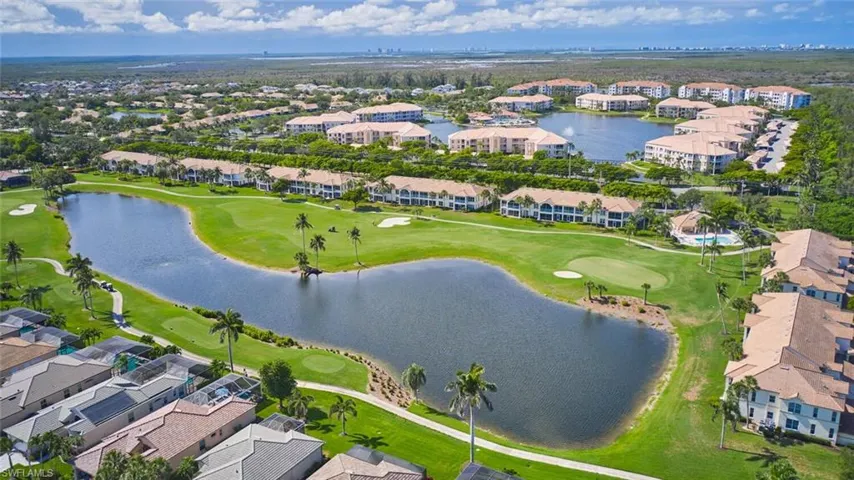 Aerial view of property and surrounding area with a golf club, a large body of water, and nearby suburban area