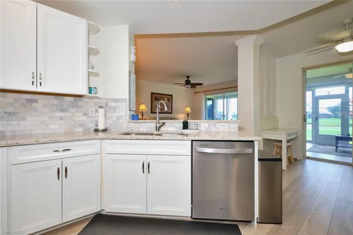 Kitchen with stainless steel dishwasher, a sink, ceiling fan, open shelves, and ornamental molding