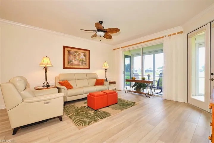 Living area featuring crown molding, light wood-type flooring, ceiling fan, and baseboards