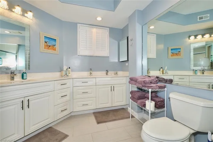 Full bath featuring toilet, a shower stall, double vanity, and recessed lighting
