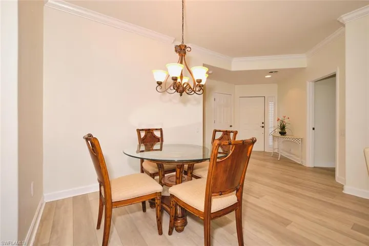 Dining area with ornamental molding, light wood-style floors, a chandelier, and baseboards