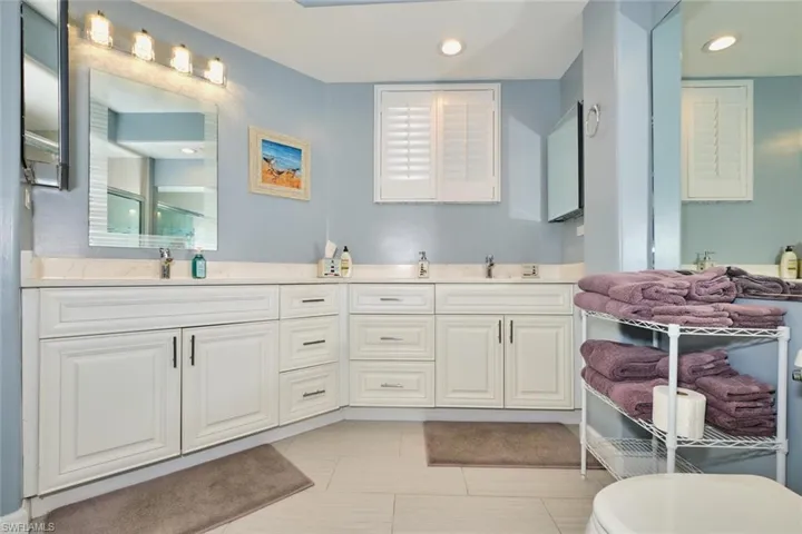 Bathroom with double vanity, recessed lighting, tile patterned flooring, and a shower
