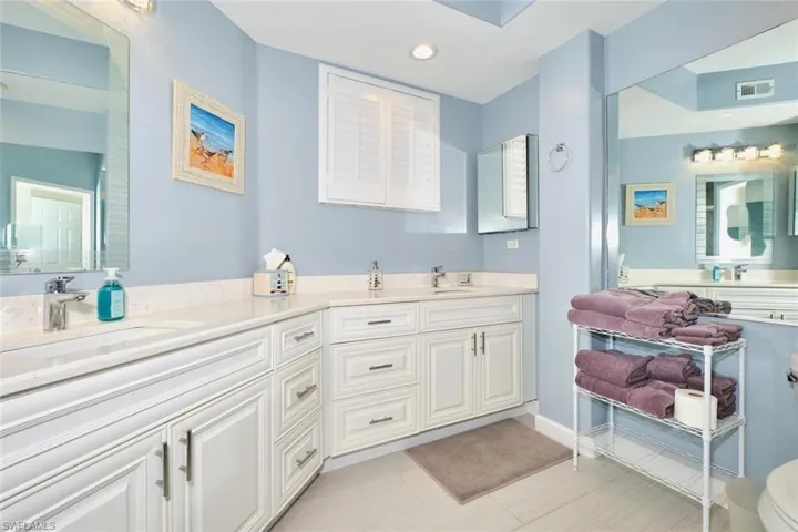 Bathroom with double vanity, recessed lighting, and baseboards