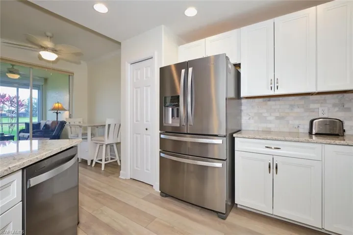 Kitchen with stainless steel appliances, tasteful backsplash, light wood-style flooring, white cabinets, and recessed lighting