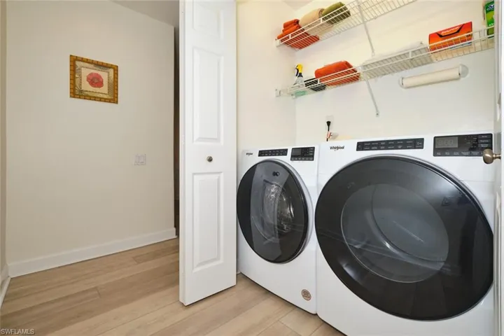 Laundry area with washing machine and clothes dryer, light wood-style floors, and baseboards