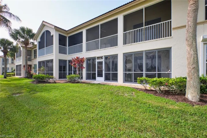 Rear view of house with stucco siding and a yard