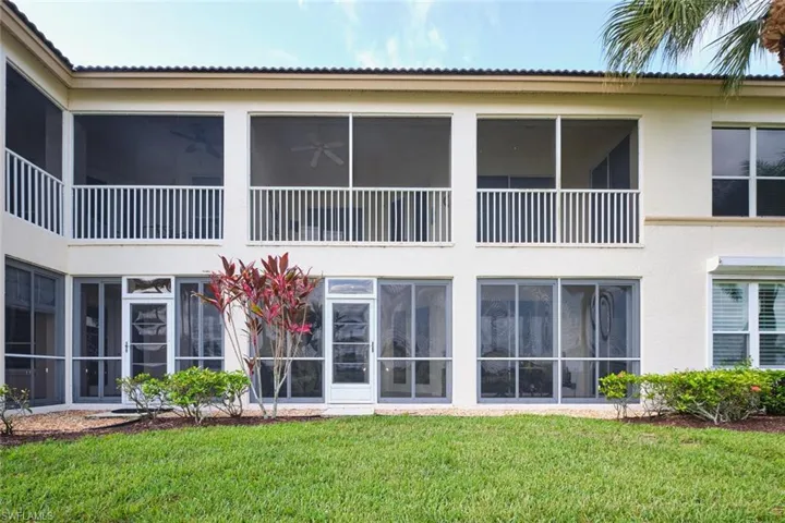 Rear view of house with stucco siding and a yard