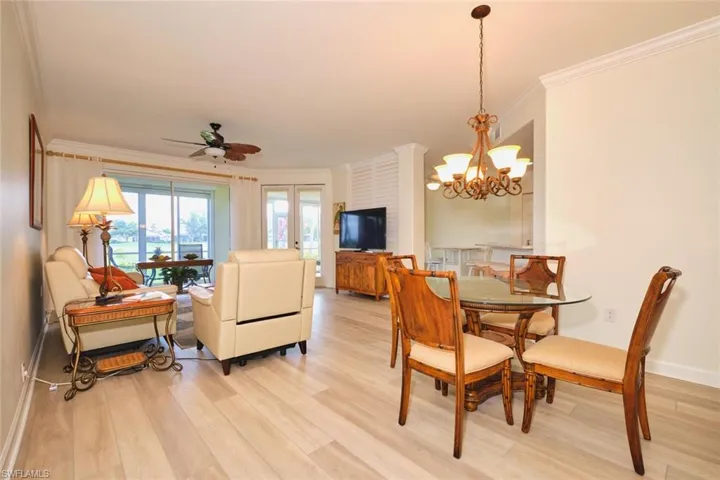 Dining room with ornamental molding, light wood-type flooring, a ceiling fan, a chandelier, and baseboards