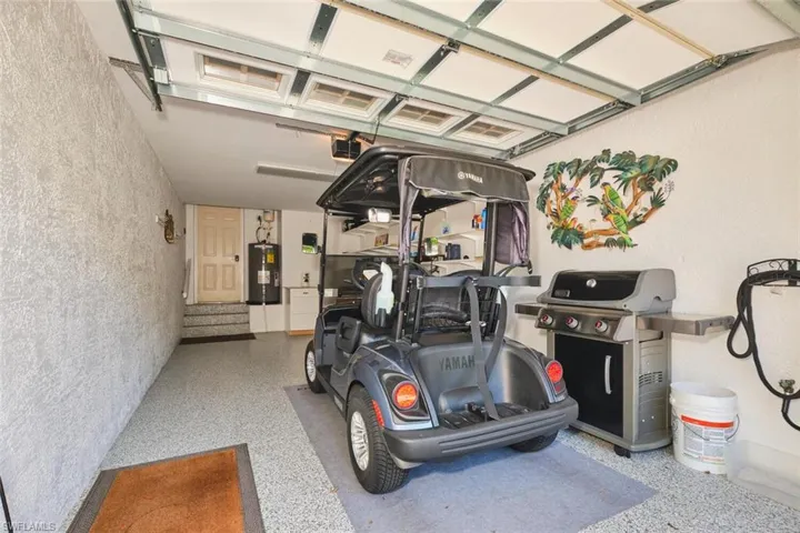 Garage with water heater, a garage door opener, and a textured wall