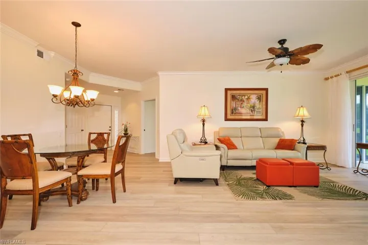 Living area featuring crown molding, a chandelier, light wood finished floors, ceiling fan, and baseboards