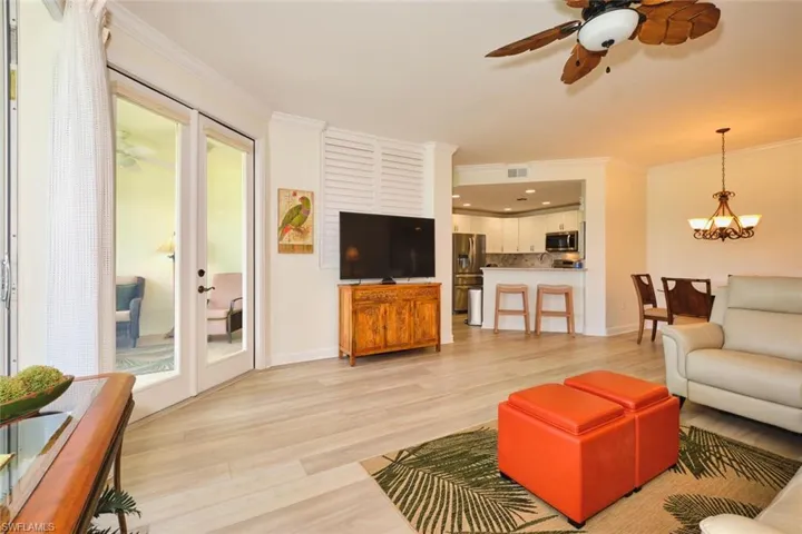 Living area featuring ornamental molding, light wood-type flooring, a ceiling fan, a chandelier, and baseboards