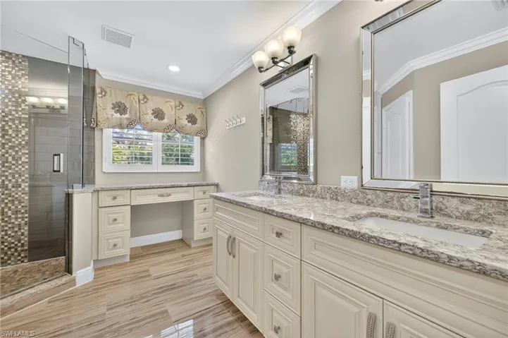 Bathroom with crown molding, a shower stall, double vanity, recessed lighting, and wood finish floors
