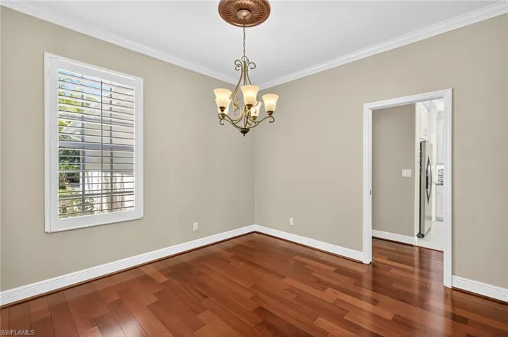 Spare room featuring ornamental molding, a chandelier, and dark wood-style flooring