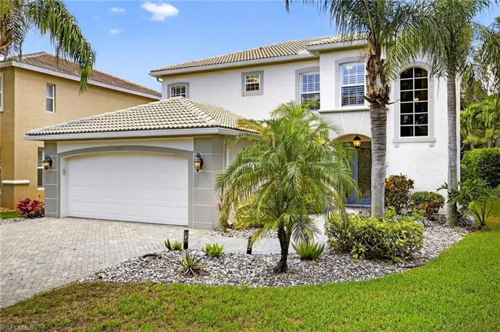 View of front facade featuring an attached garage, decorative driveway, stucco siding, and a tile roof
