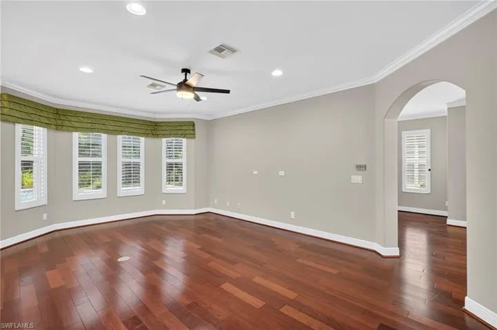 Spare room with ornamental molding, arched walkways, dark wood-style floors, recessed lighting, and ceiling fan