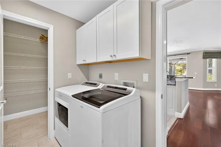Washroom featuring light wood-style flooring, cabinet space, and washer and dryer