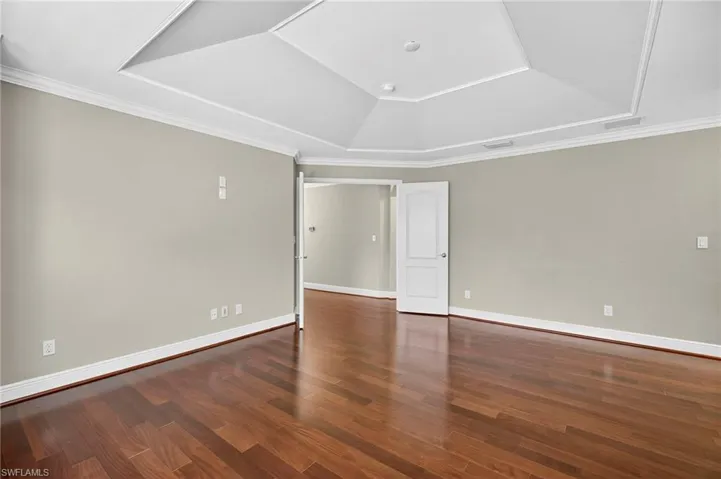 Spare room with dark wood finished floors, crown molding, and a tray ceiling